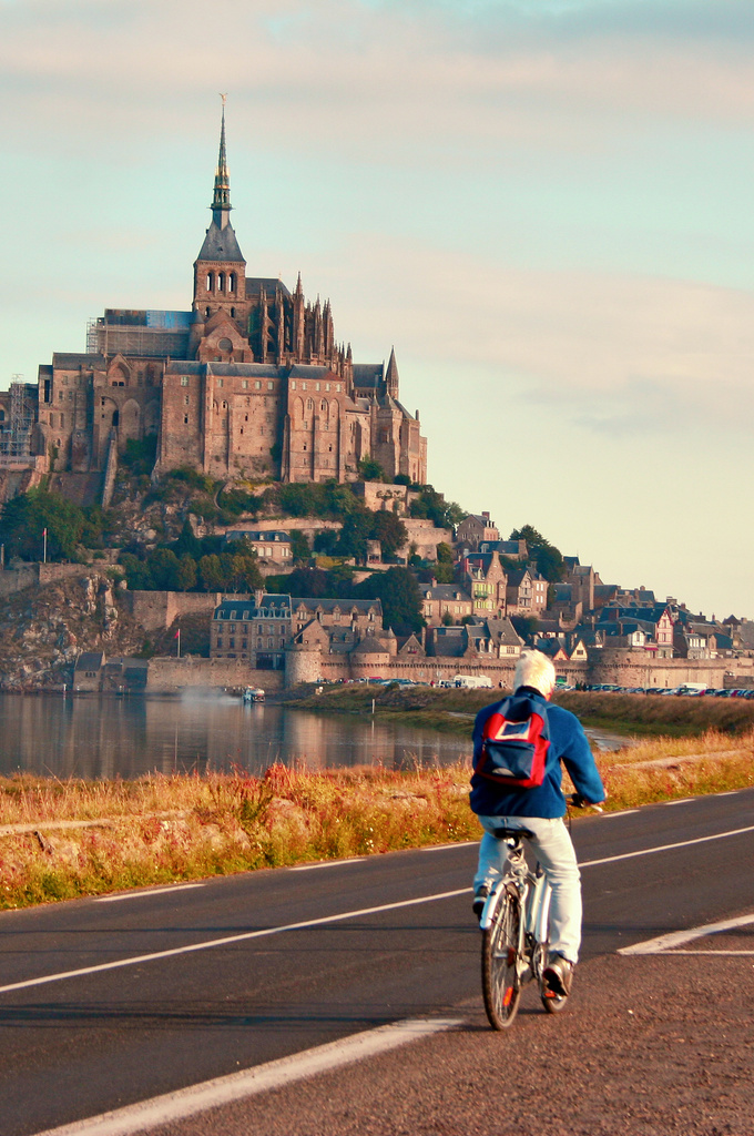 Cycliste qui avance en direction du Mont-Saint-Michel en Normandie en empruntant la route qui longe la baie
