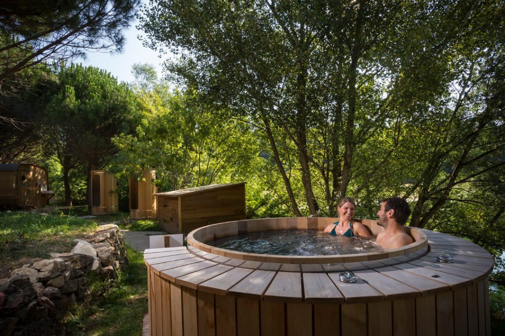 Couple dans un bain du spa forestier du camping Huttopia Dieulefit