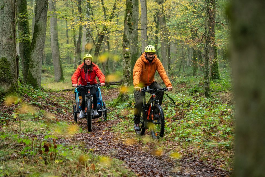 Deux personnes font du vélo dans la forêt du Perche à côté du camping Huttopia Senonches