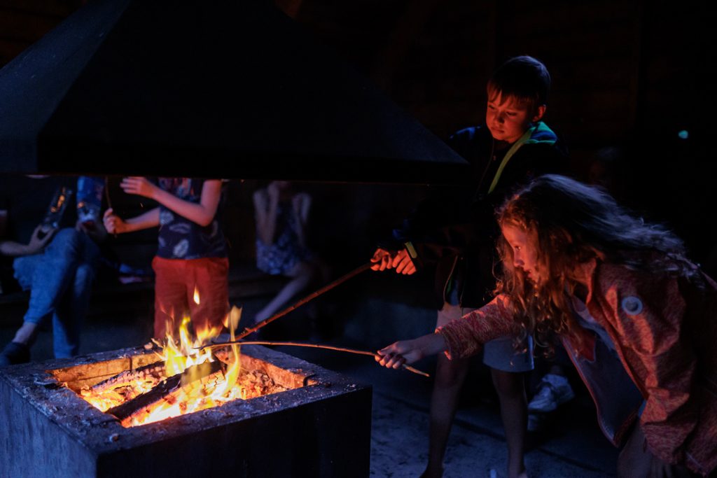 Des enfants qui font griller des chamallows au dessus du feu au camping Huttopia De Veluwe