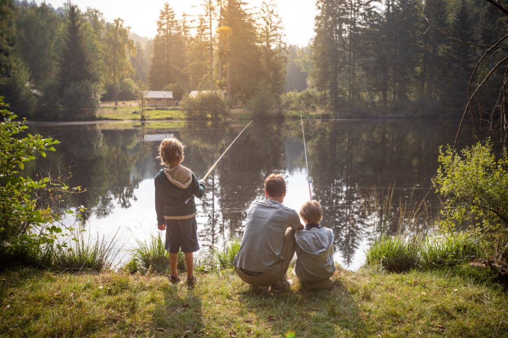 Famille qui pêche dans l'étang du camping Huttopia Forêt des Vosges à l'automne
