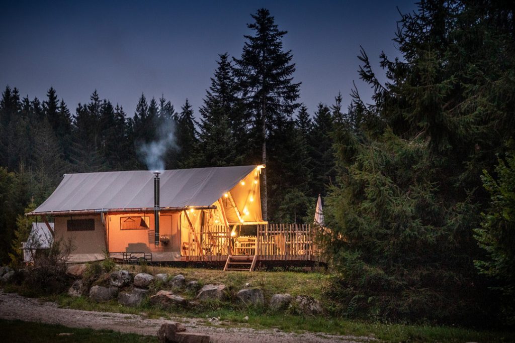 Tente Trappeur du camping Huttopia Forêt des Vosges à la tombée de la nuit