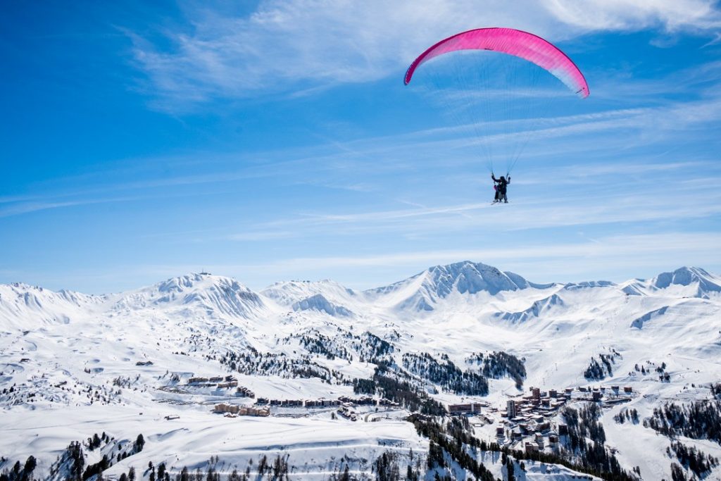 Deux personnes faisant du parapente à la montagne en hiver.