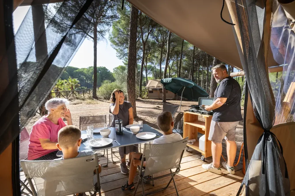 famille enfant parents grands parents en plein repas de vacances sur une tente dans un camping nature